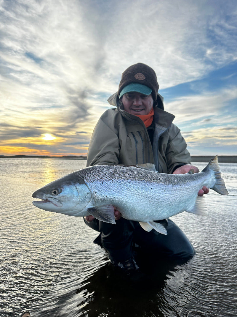 Angler holding a large trout with a sunset reflection in the the Rio Grande river