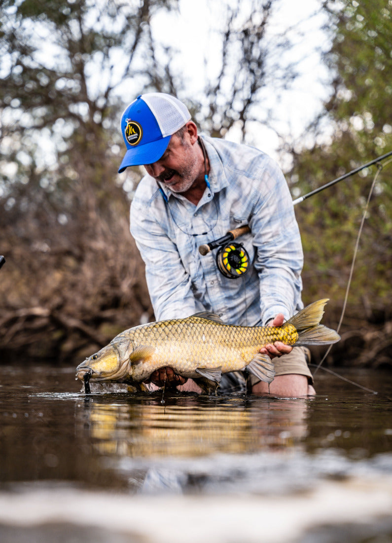 Man holding a yellowfish fish caught on the Vaal River while fishing in a natural setting